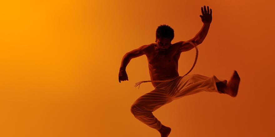 Capoeira-danser springt in de lucht met acrobatische beweging