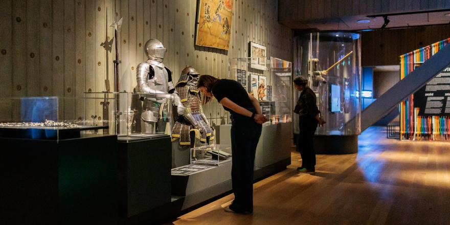 Bezoeker bekijkt historische harnassen in een museumzaal.