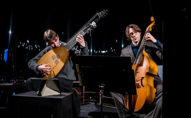 Twee muzikanten bespelen strijkinstrumenten theorbe en violone