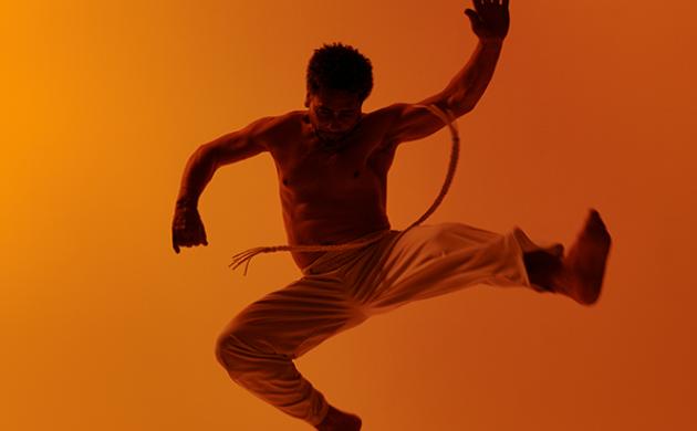 Capoeira-danser springt in de lucht met acrobatische beweging