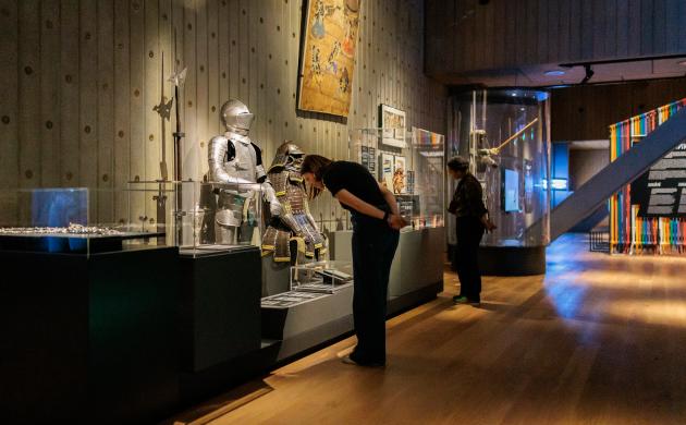Bezoeker bekijkt historische harnassen in een museumzaal.