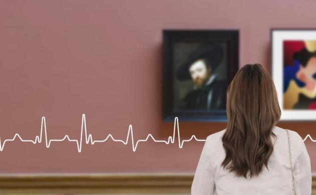 Vrouw kijkt naar het zelfportret van Ruben met ernaast een interactief scherm. Een hartslag loopt door het beeld