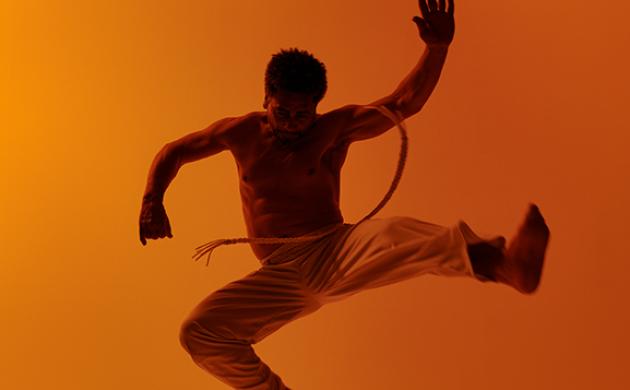 Capoeira-danser springt in de lucht met acrobatische beweging