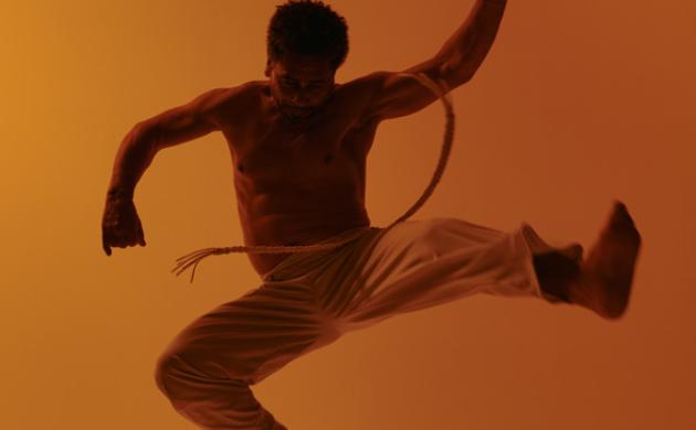 Capoeira-danser springt in de lucht met acrobatische beweging