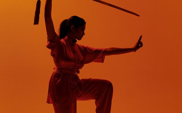 Wushu pose met zwaard op oranje achtergrond