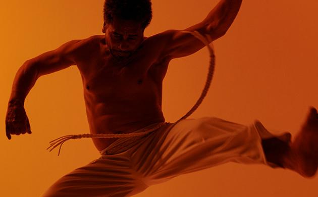 Capoeira-danser springt in de lucht met acrobatische beweging