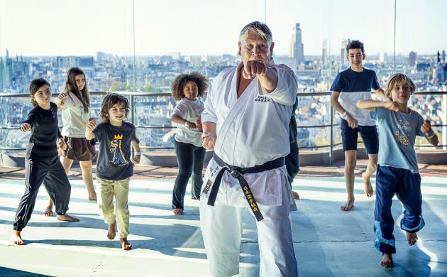 Kinderen volgen een vechtsportworkshop met een leraar.