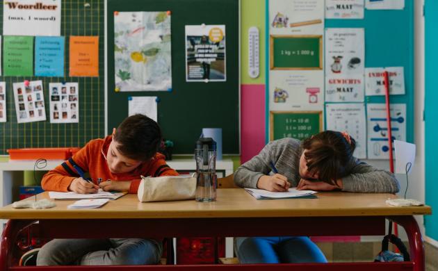 Schrijfdag De Wondere Pluim 2 kinderen zitten aan een schoolbank en schrijven