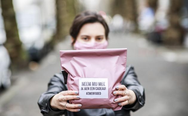 Zwerfgoed dame houdt een pakje voor zich met opschrift Neem mij mee ik ben een cadeau #zwerfgoed