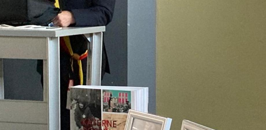 Historische foto's op een tafel naast de burgemeester die aan het woord is.