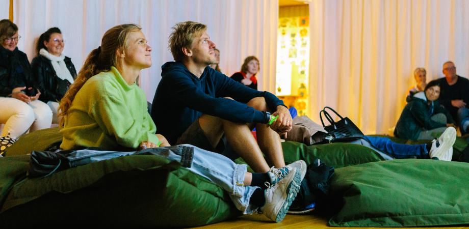 Bezoekers zitten in de expo op zitzak en kijken naar boven