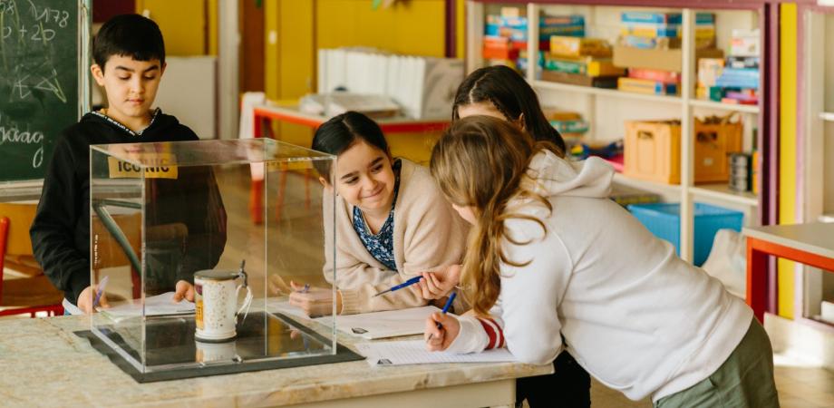 kinderen staan rond een tafel met een object in een vitrine