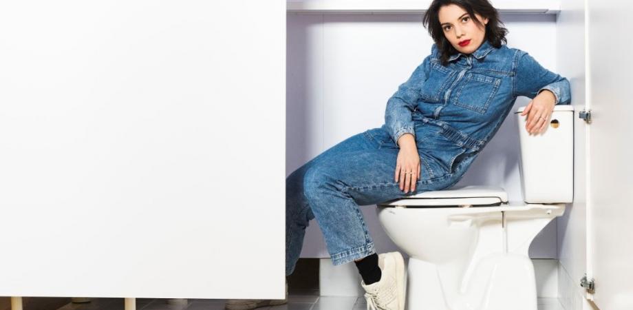 dame in jeansoverall zit op een toilet