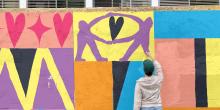 Persoon werkt aan kleurrijke muurschildering over queer verbondenheid