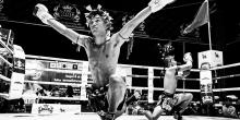 Two Muay Thai fighters perform a traditional dance in the ring.