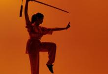 Wushu pose met zwaard op oranje achtergrond