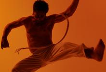 Capoeira-danser springt in de lucht met acrobatische beweging