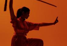 Wushu pose met zwaard op oranje achtergrond