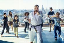 Kinderen volgen een vechtsportworkshop met een leraar.